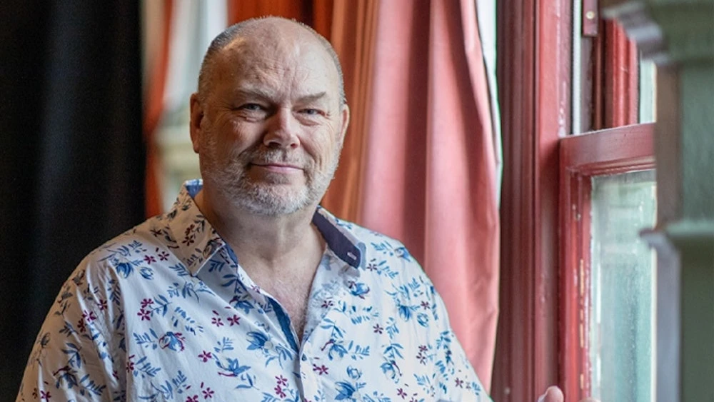 smiling-middle-aged-man-beard-floral-shirt.webp